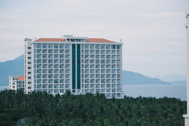 A large hotel in the distance, casting over a forest